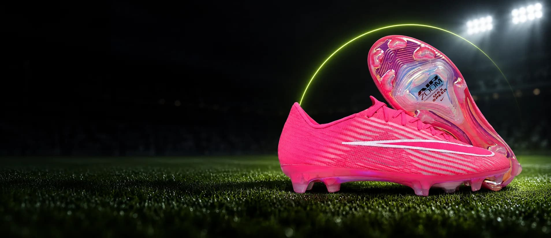 Chuteira Nike Mercurial rosa no gramado de um estádio à noite, com o arco verde-limão da Arena