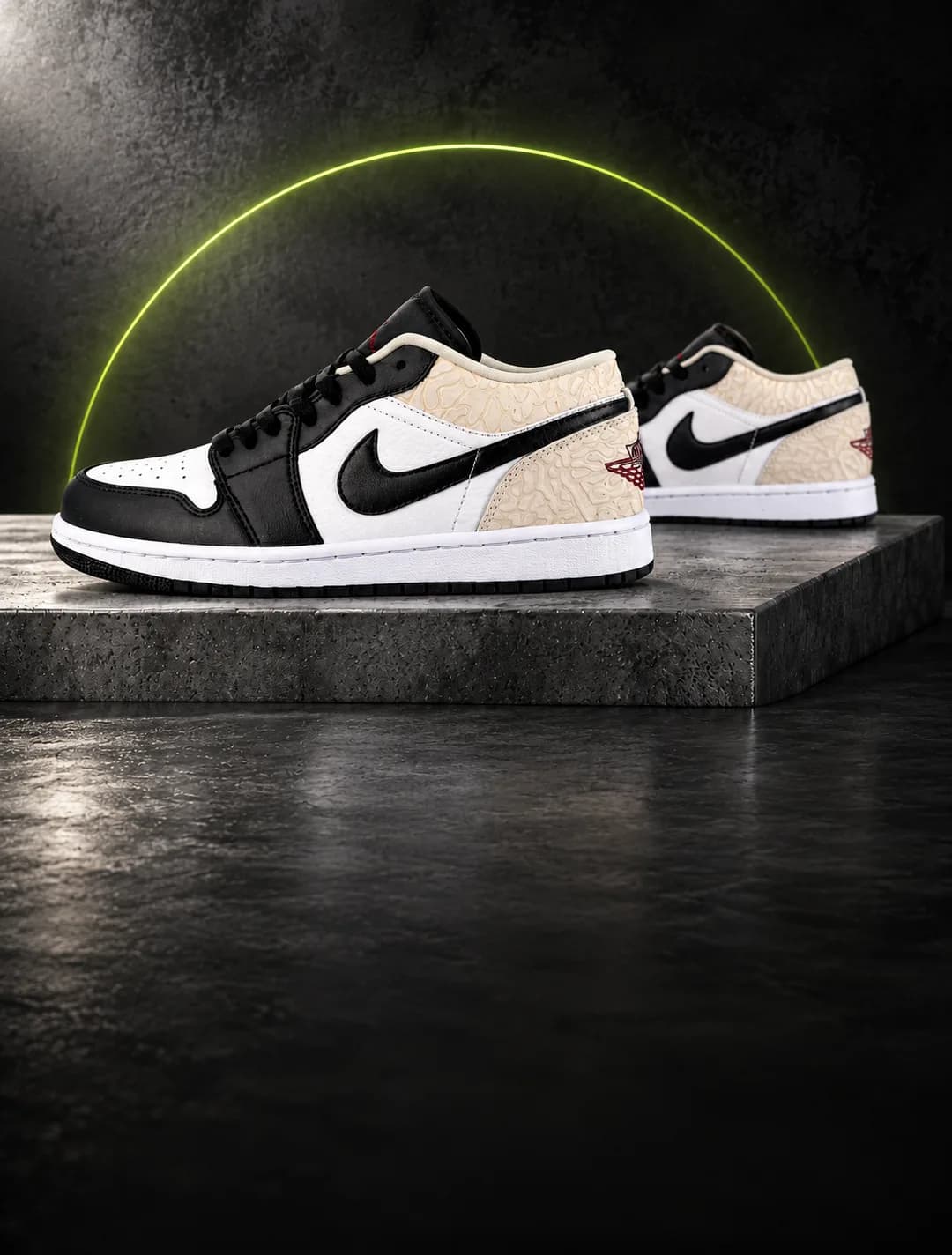 Par de Nike Air Jordan 1 Low preto, branco e bege sobre um bloco de concreto, com o arco verde-limão da Arena